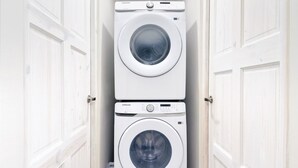 Een kleine wasruimte met twee gestapelde wasmachines.
