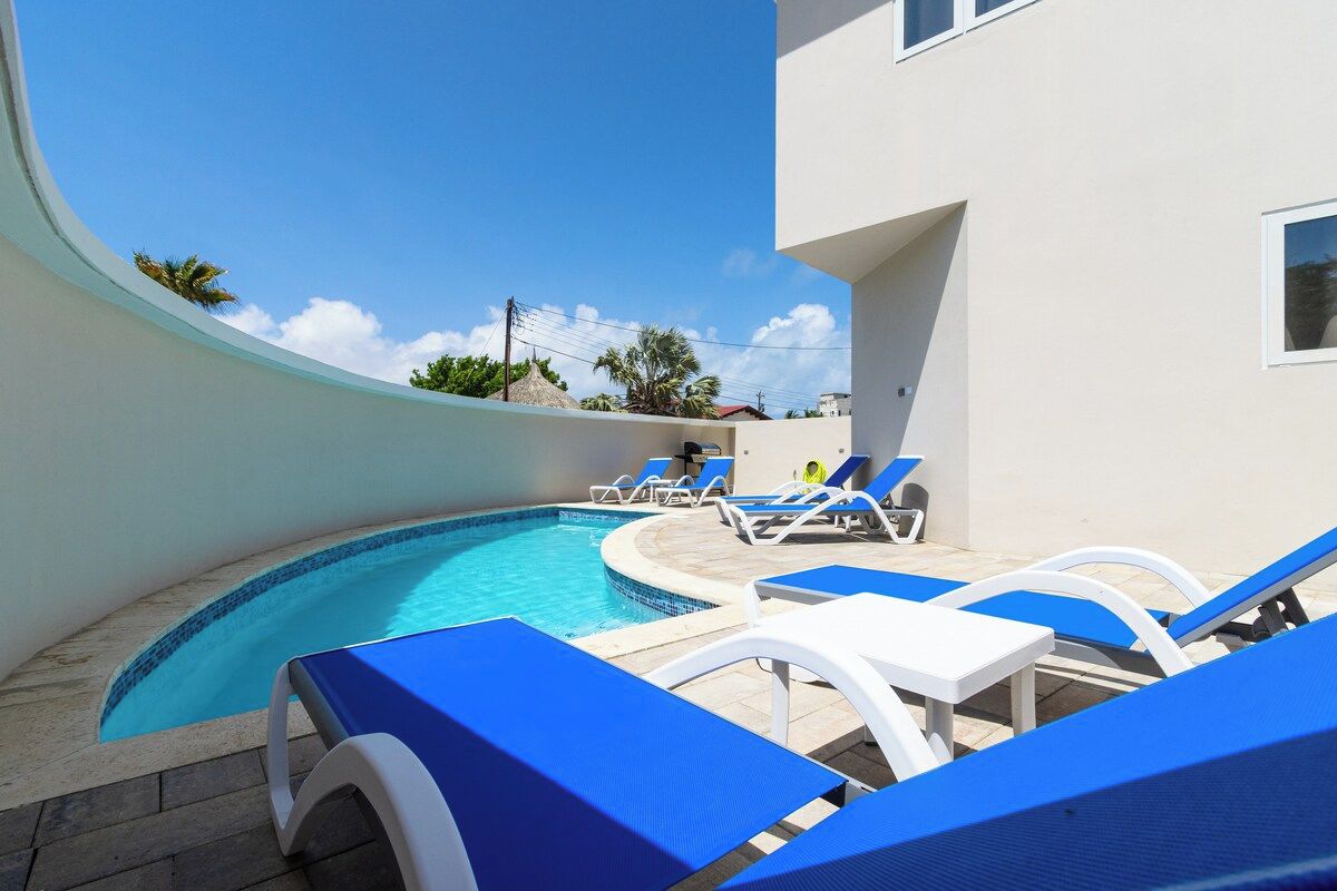 A swimming pool with lounge chairs and a building in the background.