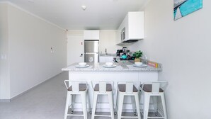 Een moderne keuken met een centraal eiland, barkrukken en een 'WELCOME'-bord.