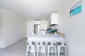 A modern kitchen with a central island, bar stools, and a 'WELCOME' sign. - Aruba Escape! 2BR Condo w Shared Pool Near Beaches (Noord)