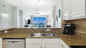 A modern kitchen with granite countertops, stainless steel appliances, and white cabinetry. - REFRESHED CONDO! READY FOR YOU! 3/2 GULF FRONT! SLEEPS 10! (Panama City Beach)