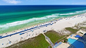 A beach with rows of blue umbrellas, a swimming pool, and a clear view of the ocean. - REFRESHED CONDO! READY FOR YOU! 3/2 GULF FRONT! SLEEPS 10! (Panama City Beach)