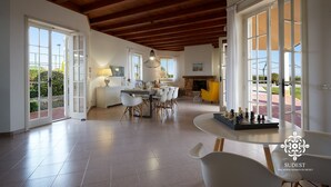 Amplia sala de estar con una mesa de comedor, sillas, chimenea y ventanas grandes.