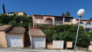 A two-story house with a balcony, a garage, and a small shed.
