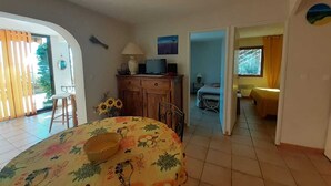A bedroom with a bed, a dresser, a desk, and a chair. There is a window with curtains and a view of the outside.