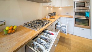 A modern kitchen with a gas stove, stainless steel appliances, and a wooden countertop. - Spacious  5 bedroom split level flat with three bathrooms and open plan kitchen living area, sleeps (Seaview)