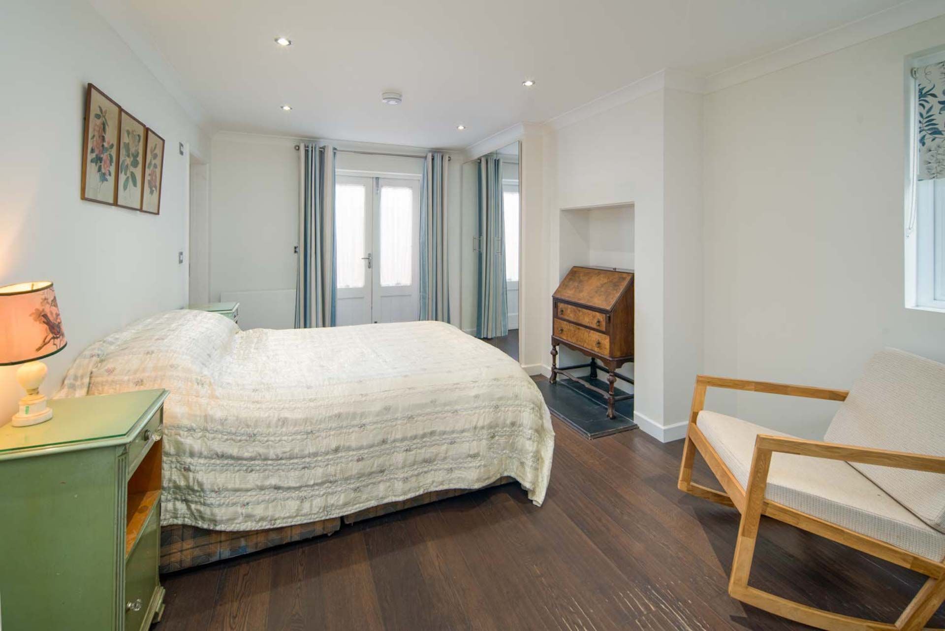 A bedroom with a bed, a wooden chair, a nightstand, and a dresser.