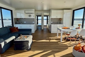 Un interior moderno con sofá, mesa de comedor, sillas y zona de cocina.