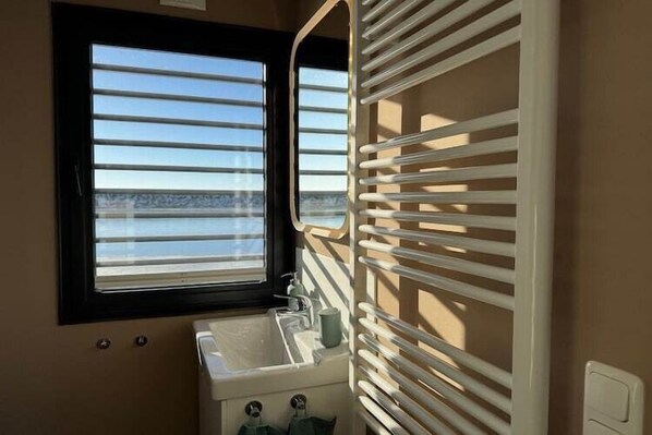 Baño con ventana, lavamanos y perchero.