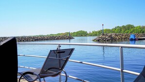 A poolside area with a chair and a view of a rocky shoreline and trees. - Hausboot in Boltenhagen (Boltenhagen)