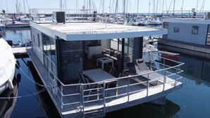 A floating structure with a glass enclosure, a dining area, and a small kitchen. - Hausboot in Boltenhagen (Boltenhagen)
