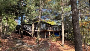 A cabin with a wooden deck, a staircase leading to a second level, and a covered outdoor area. - Secluded Lakeside Cottage in Beautiful Whitestone (Whitestone)