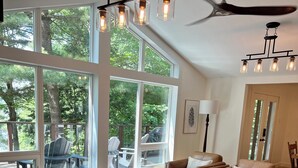 A spacious living room with large windows, a ceiling fan, and a cozy seating area. - Secluded Lakeside Cottage in Beautiful Whitestone (Whitestone)