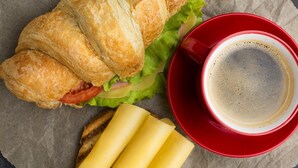 A croissant sandwich with lettuce and tomato, a cup of coffee, and a red cup. - Résidences Gamly (Mamoudzou)