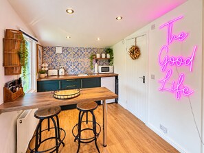Una cocina con una isla de madera, taburetes de bar, un letrero de neón y un salpicadero con diseño.