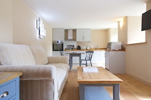 Cozy living area with a kitchenette, sofa, and small table, perfect for cooking and relaxing.