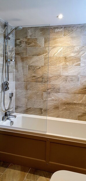 Bathroom features a bathtub, glass shower enclosure, and patterned tile floor.