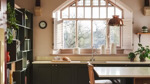A kitchen with a large window, wooden cabinets, a sink, and a dining area. - Wesleyan, Bolton Abbey Estate (Barden)