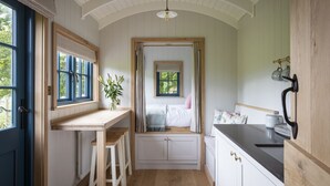 A compact kitchen with wooden cabinets, a built-in bench, and a window with curtains.