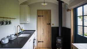A kitchen with a black stove, white cabinets, and a wooden door.