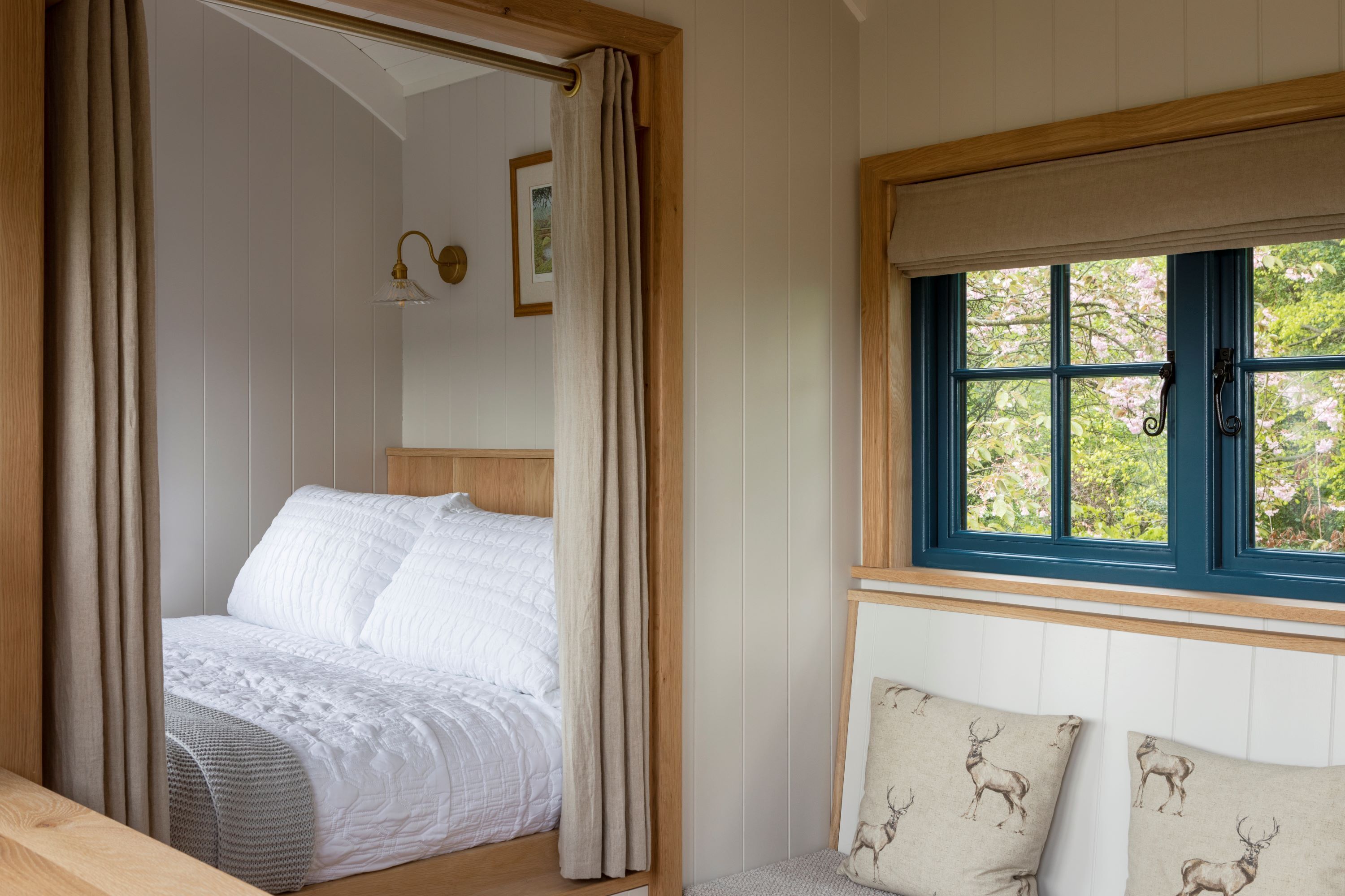 A bedroom with a bed, a window with a view of greenery, and a wooden headboard.