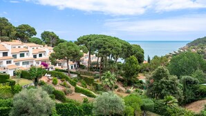 A coastal residential area with villas, lush greenery, and a clear view of the sea.