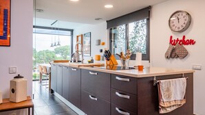 A modern kitchen with dark cabinets, a large island, and a view to the outdoors.