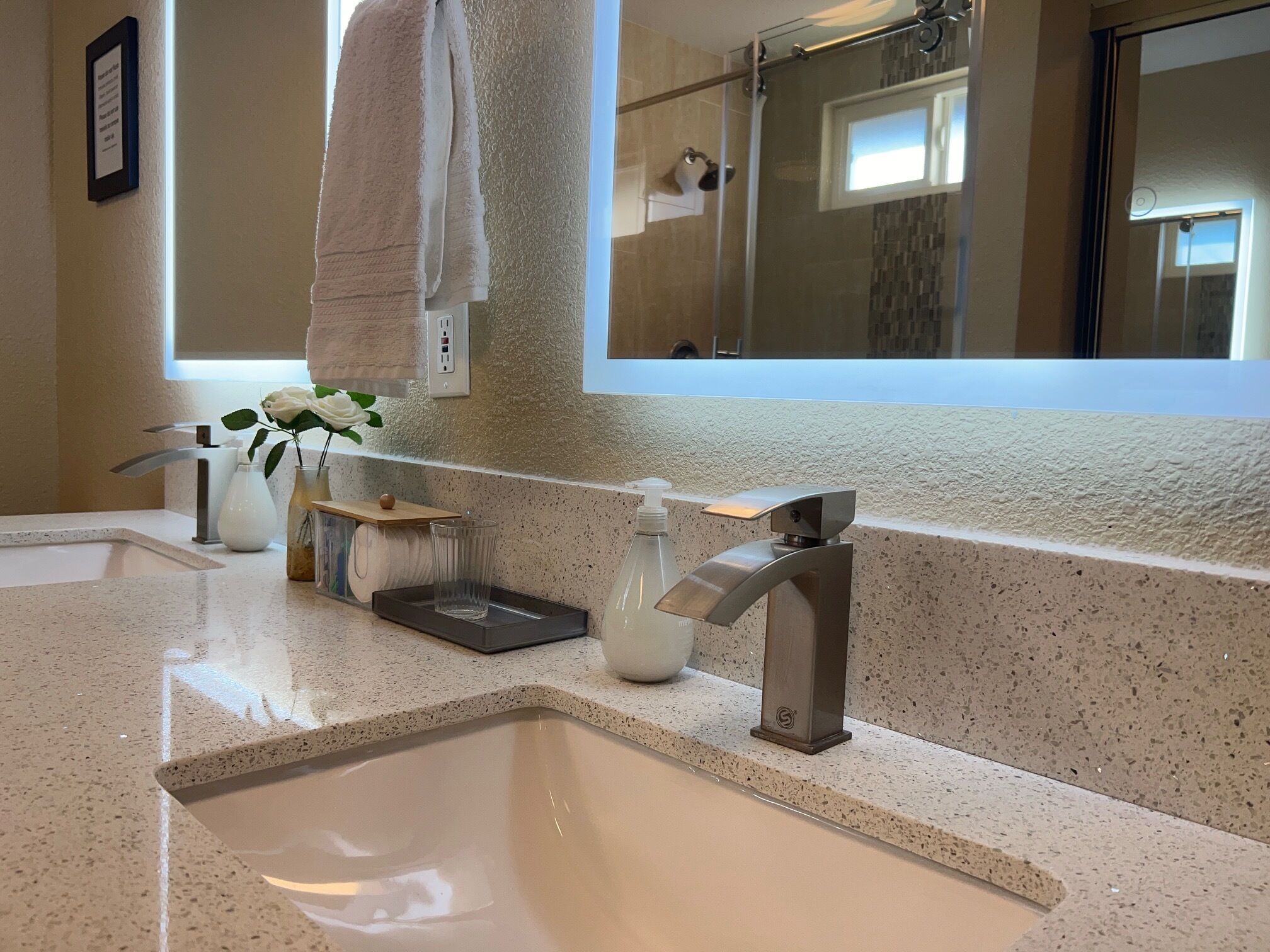 A modern bathroom with a large sink, a glass shower enclosure, and a mirror above the sink.