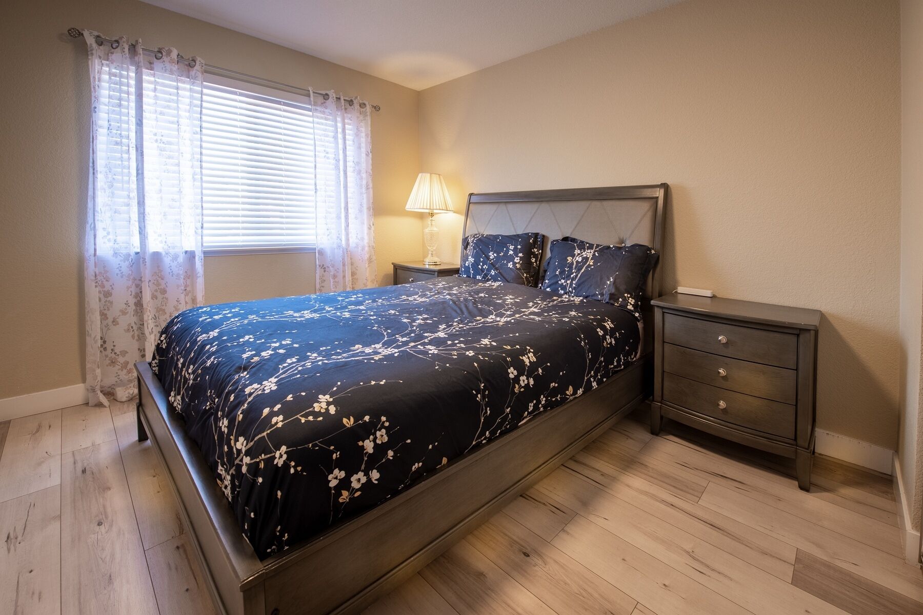 A bedroom with a bed, nightstands, a lamp, and a window with curtains.