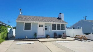 A single-story house with a front porch, a chimney, and a small yard with a picnic table and chairs. - 231 33rd St Unit A  2BR Beach Home Hideaway  Parking (Brigantine)