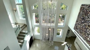 Un interior amplio con una gran araña, varias ventanas y una escalera.