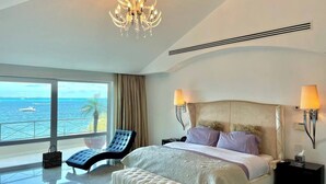 Un dormitorio amplio con una cama grande, un sillón y vista al océano.