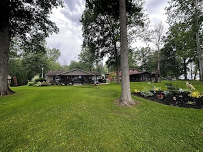 Een woonwijk met een huis, omringd door een verzorgd gazon en bomen.