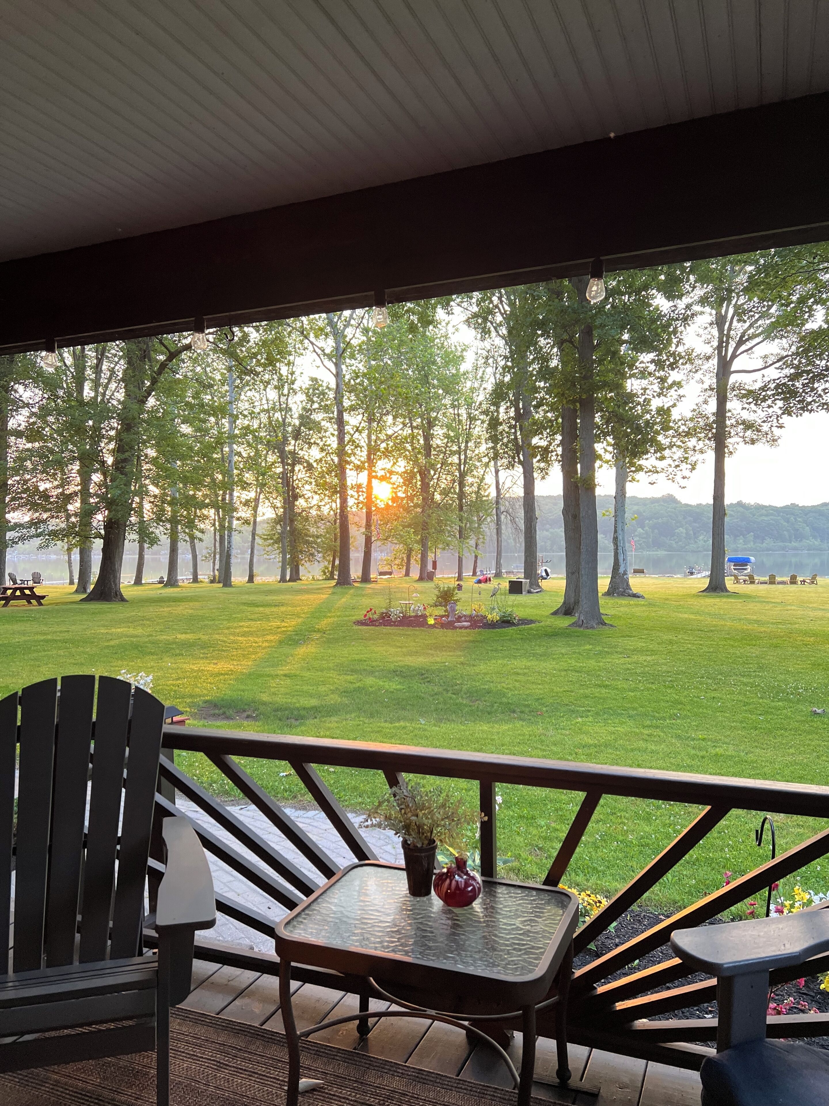 A covered outdoor seating area with a view of a grassy park and trees.