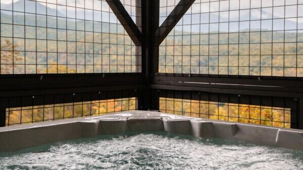 Ein Whirlpool mit Blick auf eine gebirgige Landschaft durch ein fensterförmiges Gitter.