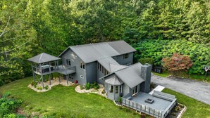 Ein modernes, zweistöckiges Haus mit überdachter Veranda, einer separaten Garage und einem angelegten Garten.