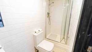 Ein kleines Badezimmer mit Toilette, Dusche und einer Glaskabine zur Dusche.