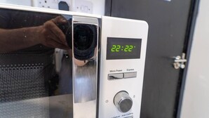 A microwave with a digital display showing 22:22, a control knob, and a power button. - Large Studio Available on First Floor! (Birmingham)