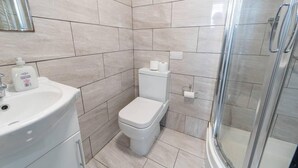 A bathroom with a white sink, a toilet, and a glass shower enclosure. - Modern Studio Available Close to the City (Birmingham)