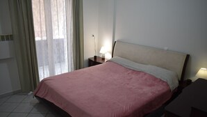A bedroom with a bed, a nightstand, a lamp, and a window with curtains. - MTC-Jasmine's House (Markopoulo Mesogaias)