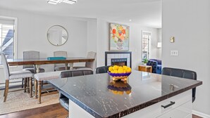 Un comedor moderno con una gran mesa de mármol, un bol de limones y una chimenea al fondo.
