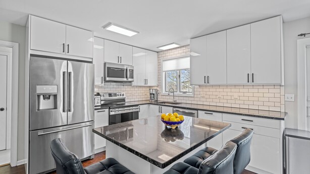 Una cocina moderna con electrodomésticos de acero inoxidable, una isla central con asientos y vistas al exterior.