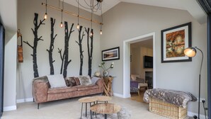 A modern living room with a sofa, a coffee table, and a wall-mounted light fixture. - Beech Lea (Ulverston)