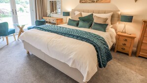 A neatly arranged bedroom with a bed, bedside tables, a desk, and a chair. - Beech Lea (Ulverston)