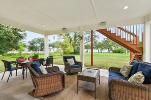 A covered outdoor seating area with wicker furniture, a staircase, and a view of the lawn. - Steps to Beach- 4 Bdrm & 3.5 Bath. Master suite + Mother in Law suite. (Gulfport)
