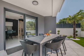 A modern patio with a dining table, chairs, and a fruit bowl.