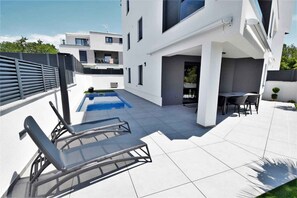 A modern building with a swimming pool, lounge chairs, and a patio area. - Holiday apartment with pool (Njivice)