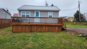 A two-story house with a wooden deck and a blue door. - Cozy North Shore two bedroom cottage (York)