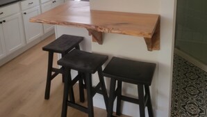 A kitchen with white cabinets, a wooden countertop, and two black stools. - Cozy North Shore two bedroom cottage (York)