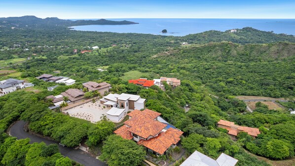 An aerial view of a residential area with houses, roads, and a large body of water in the background.
